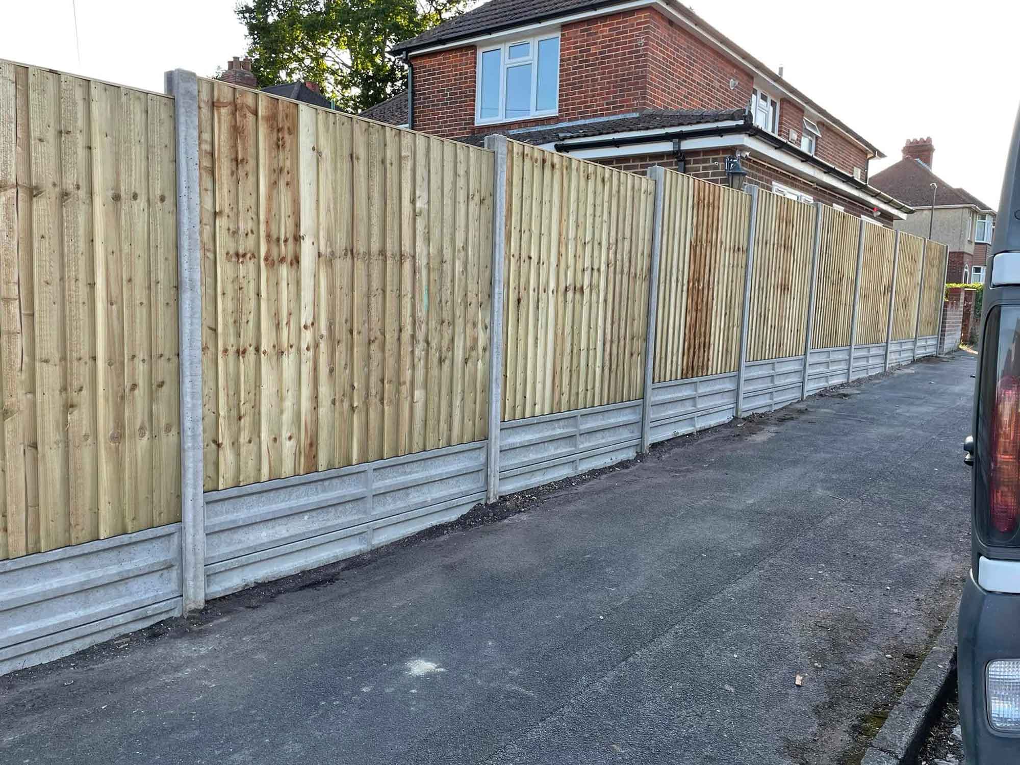 Closeboard fence installation with concrete posts.